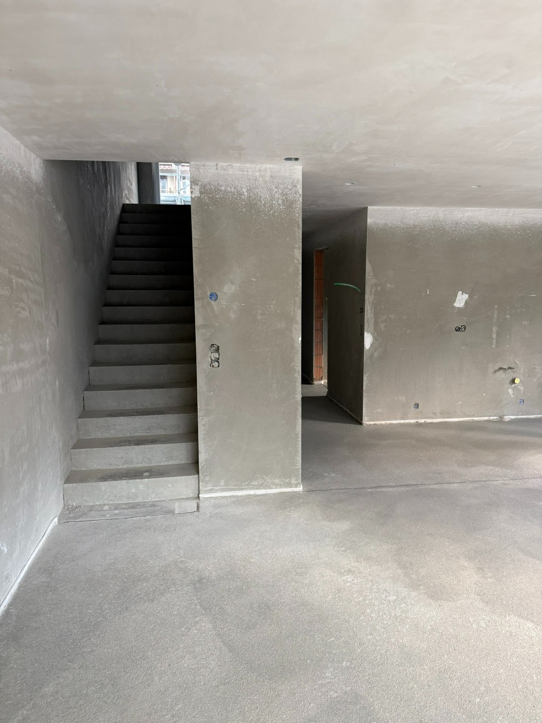 Unfertiger Innenraum mit Betonwänden und Treppe, bereit für weitere Bauarbeiten oder Renovierung.